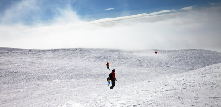 Skiers and snowboarders downhill on snowy slope
