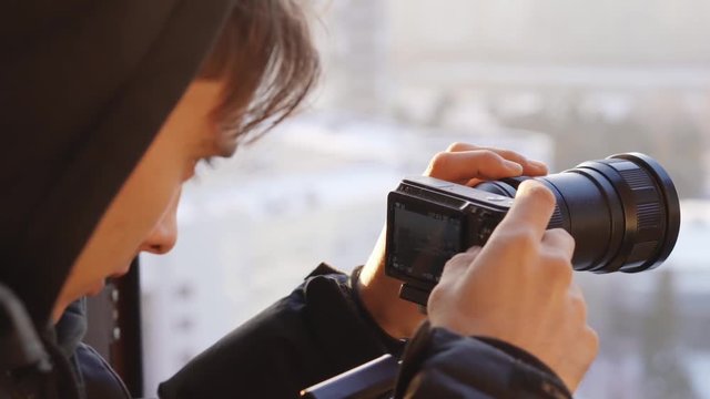 young man sets camera settings on the window background