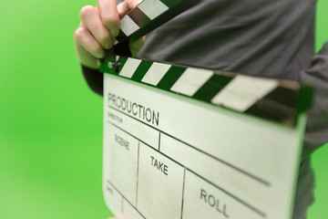 Video producer man holding movie clapper board on green background