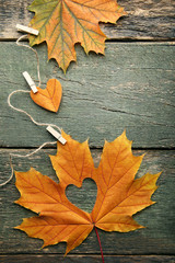 Naklejka na ściany i meble Dry maple leafs with heart on grey wooden table