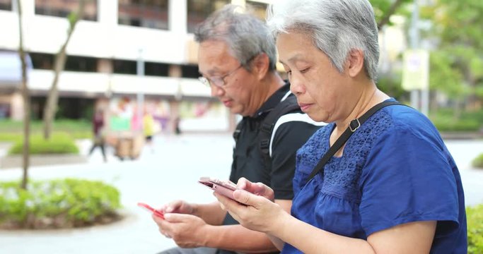 Old couple using mobile phone together