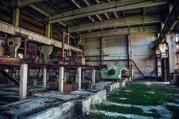 Ruins of abandoned industrial factory, large warehouse or hangar building with rusty equipment and machine tools