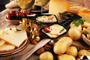 Plexiglas foto achterwand Delicious traditional Swiss melted raclette cheese on diced boiled or baked potato served in individual skillets. © beats_