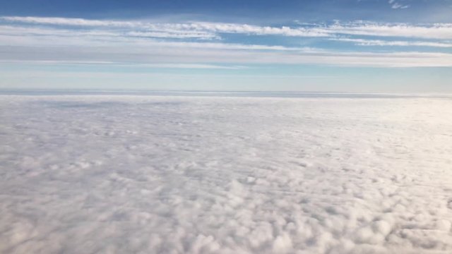 Flying above the clouds, view through an airplane window.