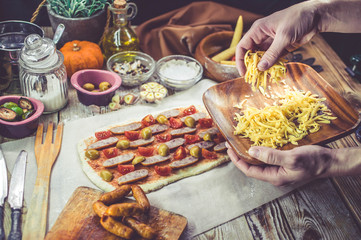 Female hand sprinkles cheese on pizza. The woman makes home-made pizza. Home-made pastries. Mediterranean traditional cuisine. Selective focus. Easy toning