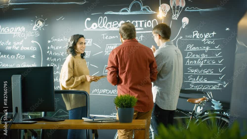 Poster Female Developer with Tablet Computer Talks With Programer and Project Manager, They use Blackboard Wall as a Planner.   Shot on RED EPIC-W 8K Helium Cinema Camera.