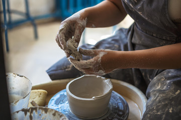 Potter girl works with clay on pottery wheel