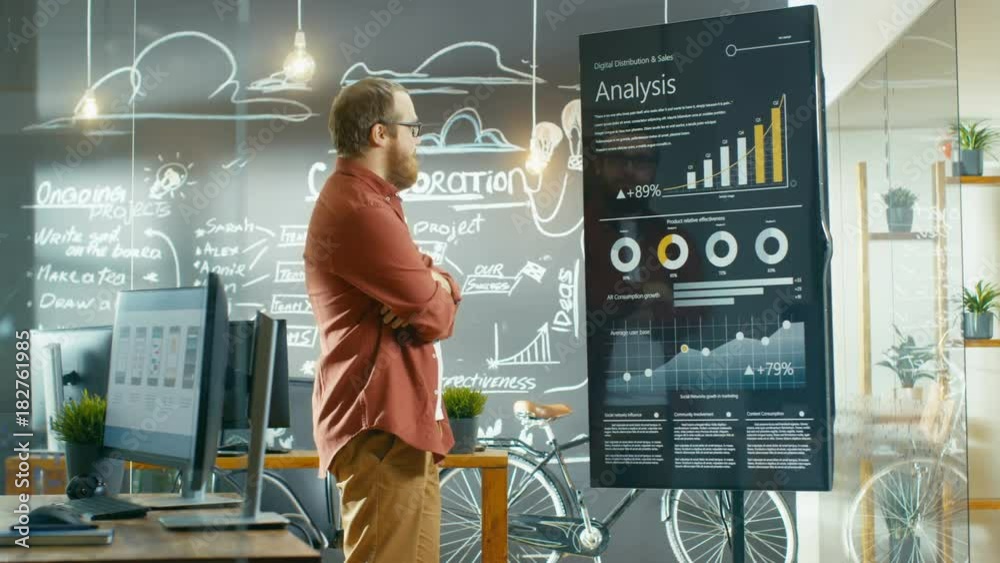 Aufkleber Marketer Looks at Interactive Touchscreen Whiteboard Showing Latest Graphs and Charts on Statistical Growth. He Works in the Creative Office. Shot on RED EPIC-W 8K Helium Cinema Camera.