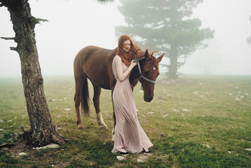 a girl next to a horse in the background of a forest and cool nature