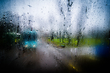 Waterdrops on a glass surface windows with closeup cityscape background