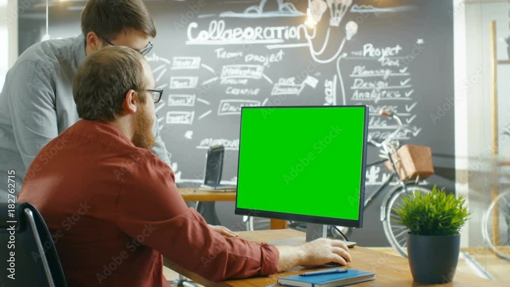 Poster Two Male Developers Talk about Project, while Personal Computer Has Green Mock-up Screen. They Work in the Creative Agency. Shot on RED EPIC-W 8K Helium Cinema Camera.