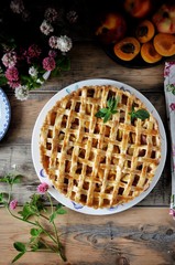 On a wooden table on a plate, a pie with apricots