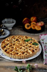 On a wooden table on a plate, a pie with apricots