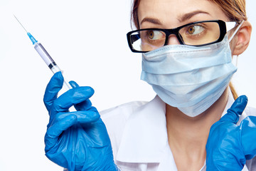 doctor in a mask holds a syringe on a white background, portrait