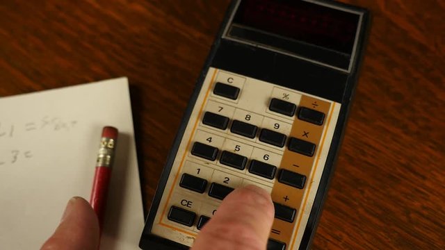 A man doing math calculations on a vintage electronic calculator