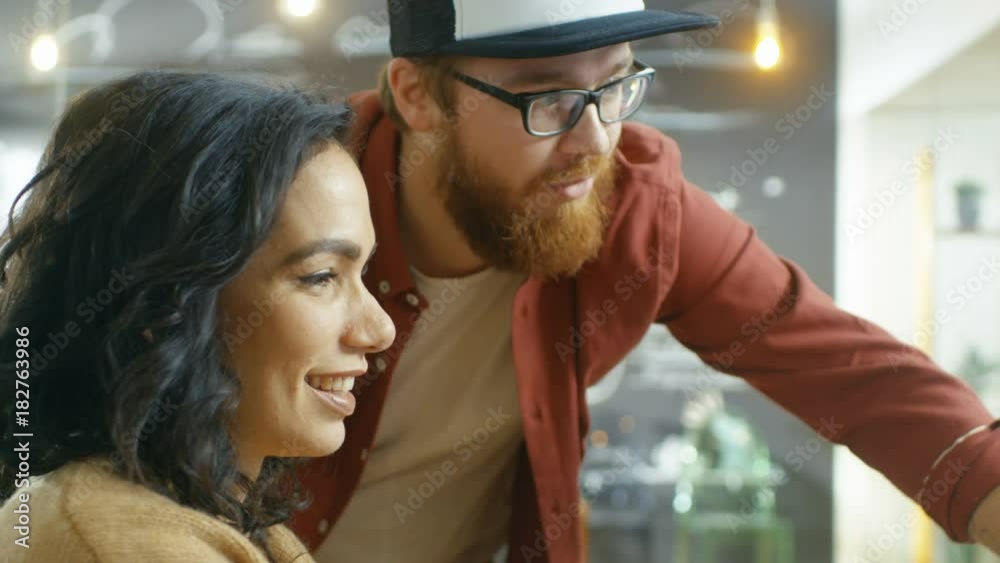 Poster Beautiful Woman Developer Uses Personal Computer and Talks With a Programer, Together They Design New Mobile Video Game/ Application. Shot on RED EPIC-W 8K Helium Cinema Camera.