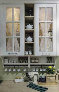 Cozy cuisine in the style of Provence. Shelf with glass doors, a wooden table top and neatly arranged dishes