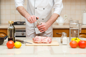 Man's hand holds bottle with souce. Professional cook prepare the meat