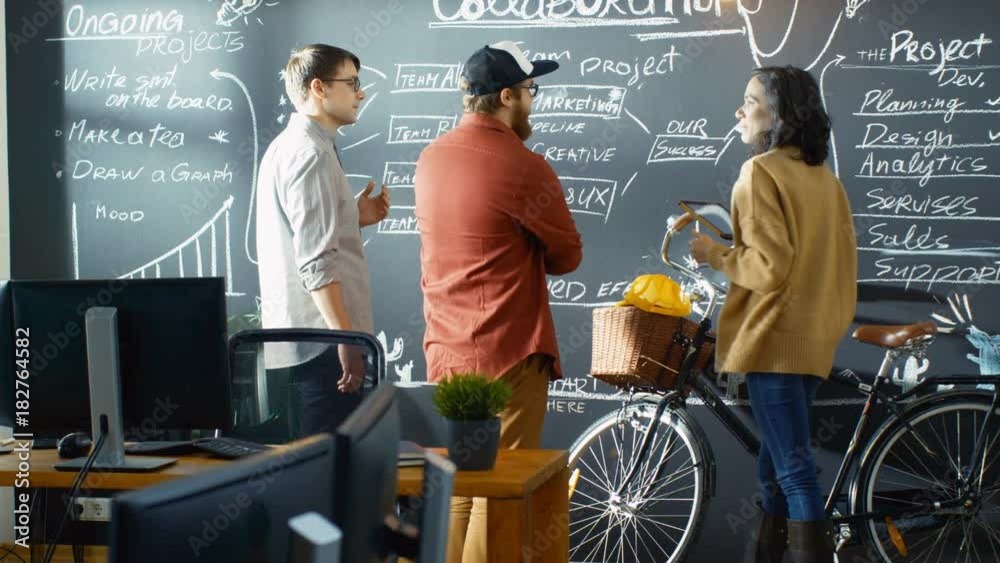 Poster Female Developer with Tablet Computer Talks With Programer and Project Manager, They use Blackboard Wall as a Planner. Shot on RED EPIC-W 8K Helium Cinema Camera.