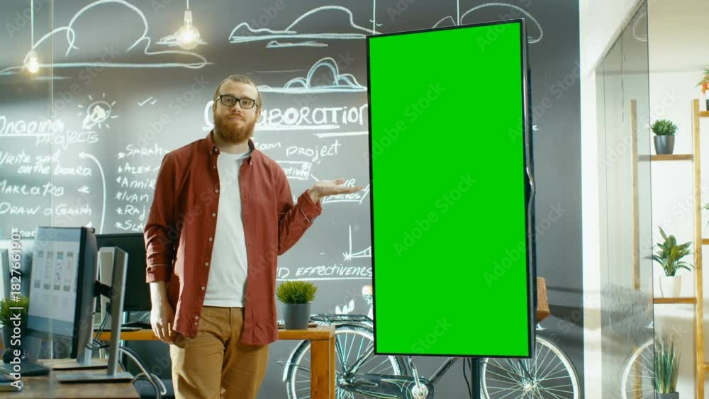 Poster male developer looks at interactive whiteboard with mock-up green screen. he points at the screen wi