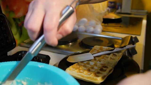 Viennese waffles waffle iron pile of orange. Man prepares Viennese waffles in the kitchen. ooking Viennese waffles