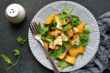 Autumn persimmon salad with arugula and parmesan cheese.Top view.
