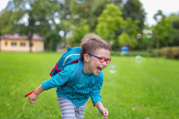 Young happy boy running in the grass at the park on a summer day