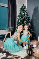 Mother and little daughter posing in the new year interior
