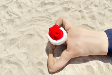 Man in Santa hats  lying on the sand. Top view