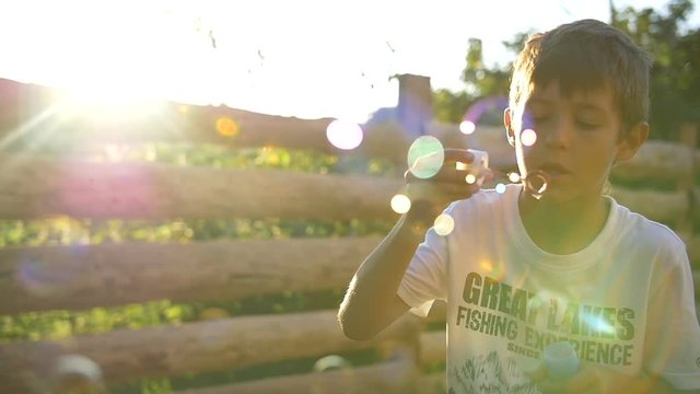 Boy Blowing Soap Bubbles At Sunset