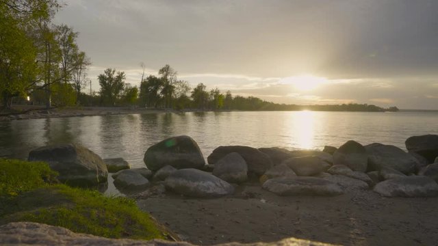 Static shot of lake simcoe from the rocky shore at sunset, with jetskier in the far distance