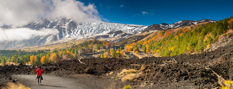 Mount Etna, Italy: panorama of the northern side of the volcano and a hiker walking on a lavic pathway