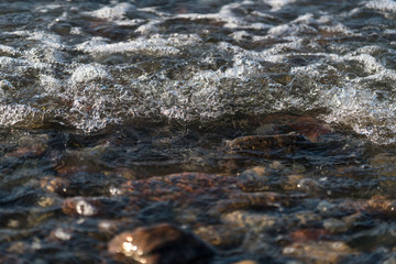 Obraz premium Fala piankowa nad skałami i plażą