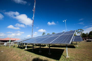 Solar panels and wind turbines generating electricity is with blue sky background