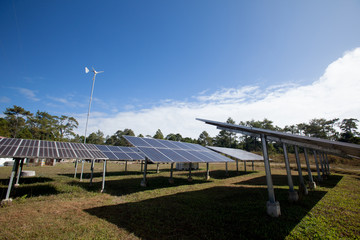 Solar panels and wind turbines generating electricity is with blue sky background