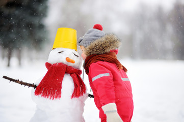 Little boy tell snowman about his secrets or gifts for Christmas