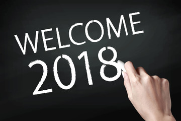 Fototapeta premium Hand holding a chalk and writing welcome 2018