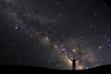Fototapeta na wymiar landscape with milky way, Night sky with stars and silhouette of a standing sporty man with raised up arms on high mountain.