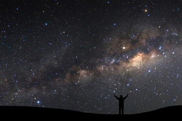 landscape with milky way, Night sky with stars and silhouette of a standing sporty man with raised up arms on high mountain.
