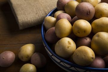 Raw fresh potatoes in a bowl on wooden background