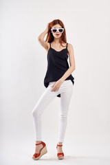 Girl posing on a white background in a black T-shirt and light jeans