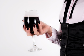 Red wine glass in elegant female hand with black nails. Close up