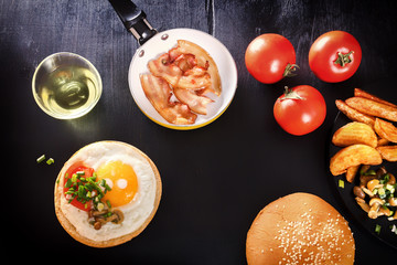 Fried egg on bread. English breakfast with bacon, fried potatoes, mushrooms and greens. Black background.