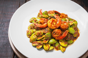 Thai food on white plate and wooden table, Spicy stir-fried shrimp with bitter or twisted cluster or stink bean ( sataw ) and shrimp paste