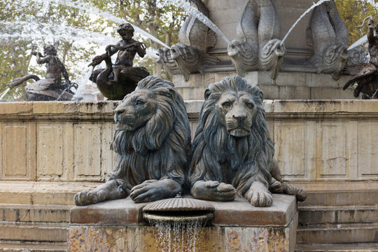 Lions of the Fontaine de la Rotonde in Aix en Provence, France, with fish and swan with angel fountains in the background.