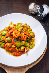 Thai food on white plate and wooden table, Spicy stir-fried shrimp with bitter or twisted cluster or stink bean ( sataw ) and shrimp paste