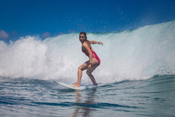 Indonesia, Bali, July 23 2016: A female surfer, Leonor Fragoso riding big blue ocean surfing wave, shot from water level