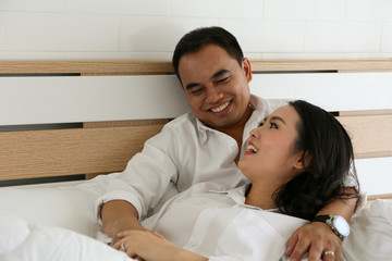 Happy Asian couple lying down on the bed together