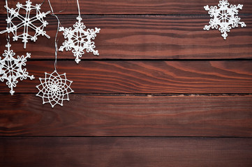 Christmas background decoration with snowflakes flat lay on dark wooden texture. Top view with blank space.