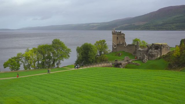 Ruins of a Scottish Castle and Tourists on the Lake